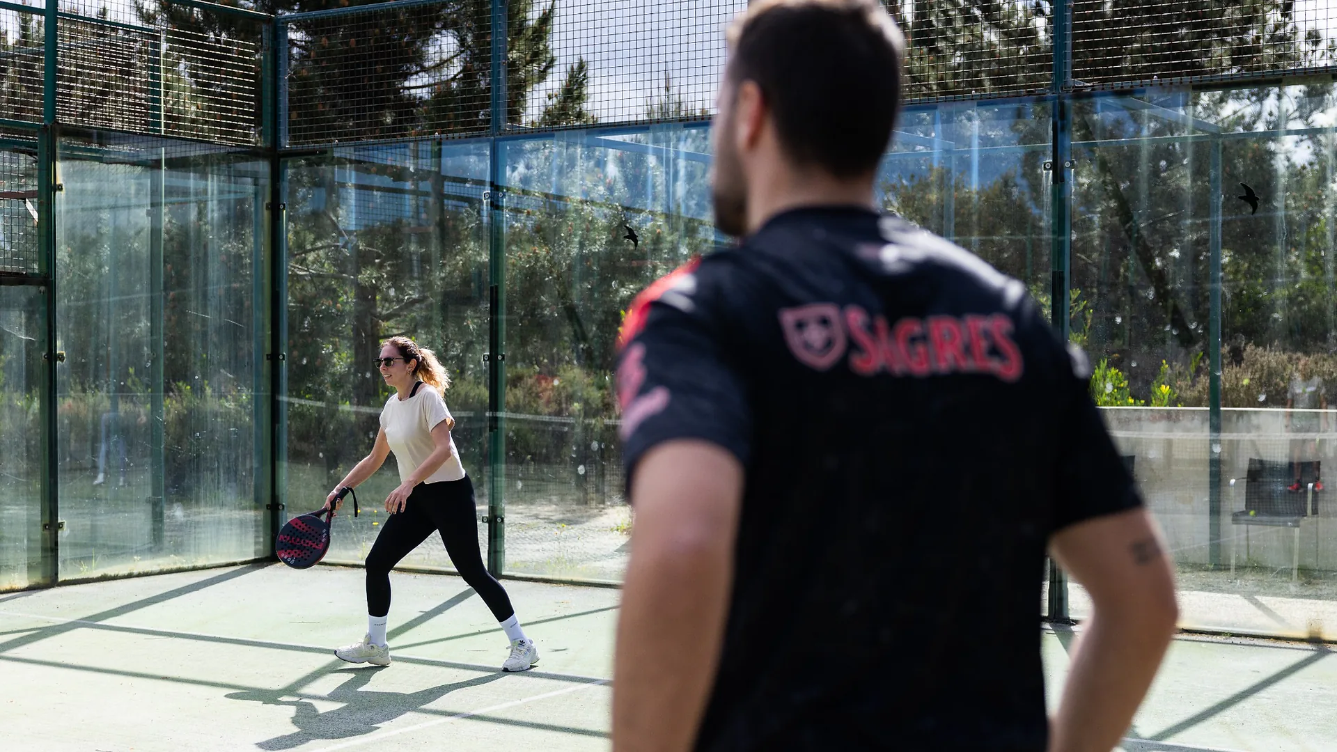 Man in a black Mapify t-shirt standing calmly with eyes closed, practicing breathing exercises outdoors with colleagues.