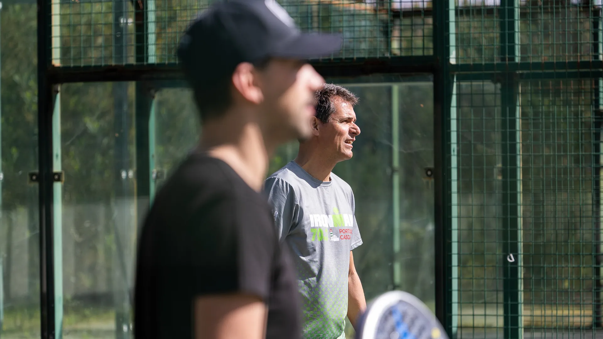 Man in a black Mapify t-shirt standing calmly with eyes closed, practicing breathing exercises outdoors with colleagues.