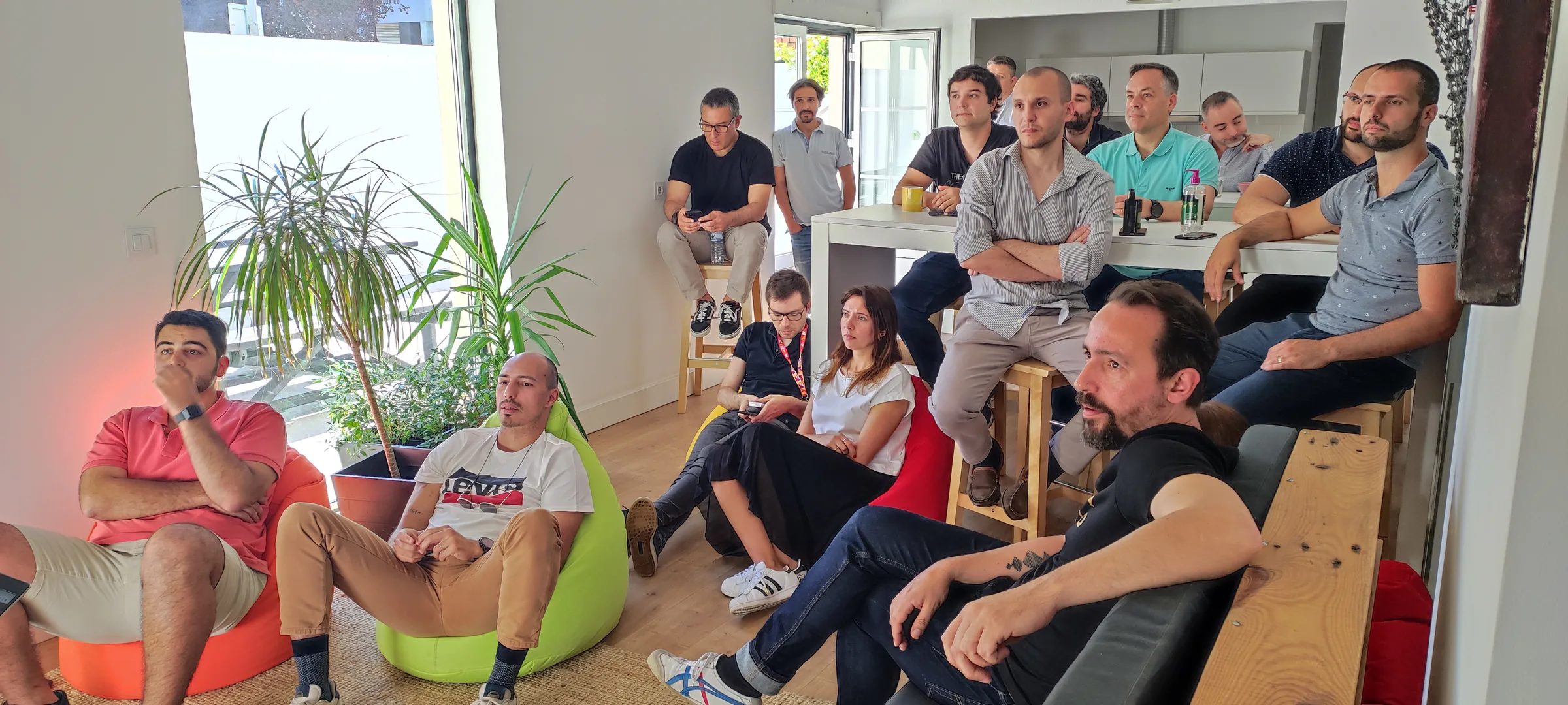 Focus BC team seated in a bright office lounge, attentively watching a presentation during an informal team meeting. Managed content for Focus BC.